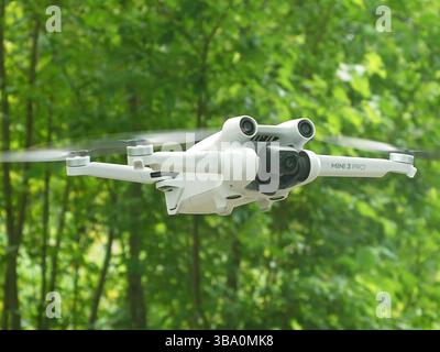 Drone DJI Mini3 Pro - remote controlled quadcopter- in flight on green nature background, Bavaria, Germany Stock Photo