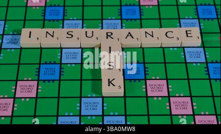 The words Insurance Risk spelt out on a Scrabble board to illustrate the concept of risk. Stock Photo
