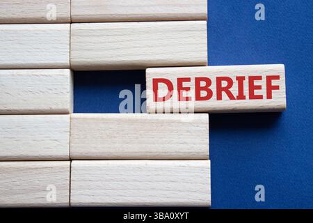Debrief symbol. Concept word Debrief on wooden blocks. Beautiful deep blue background. Business and Debrief concept. Copy space. Stock Photo