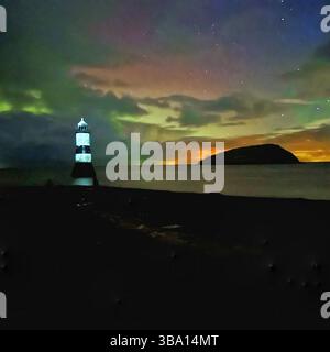 Aurora borealis over Penmon Point lighthouse and Puffin Island, Anglesey, Wales. Colourful clouds and beach visible. Taken on 5 November 2023. Stock Photo