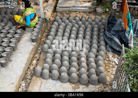 A woman engaged in arranging and making handcrafted concrete pots at a traditional pottery workshop Stock Photo
