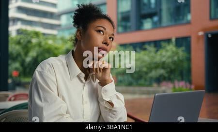 Thoughtful African American woman working laptop computer thinking ponder female girl businesswoman pensive puzzled city employer plan solution deep Stock Photo