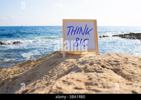 Think big symbol. Concept words Think Big on white chalk background. Beautiful sea background. Business and Think big concept. Copy space. Stock Photo