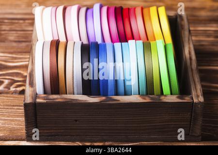 Various colors ribbon bobbins in vintage wooden box Stock Photo