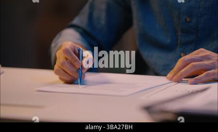 Arabian Indian man guy businessman writing notes on desk male business employer manager executive lawyer worker in late night office overtime work Stock Photo