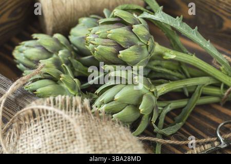 Two artichoke bouquets on kitchen table among some kitchen items. Top view Stock Photo