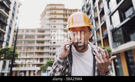 Engineer talking on phone. Architect using phone on construction site. Foreman phone call control process. Construction worker communications in const Stock Photo