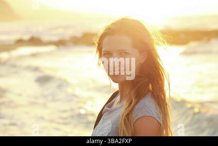 Young woman on the beach during sunset, strong backlight sea in background, detail on her smiling face, Lapta, Cyprus, Europe Stock Photo