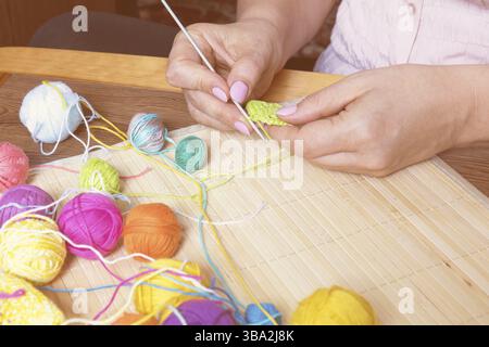 Colorful clews yarn and crochet hook on wooden background. Female hand crocheting. Toned and processing photos Stock Photo