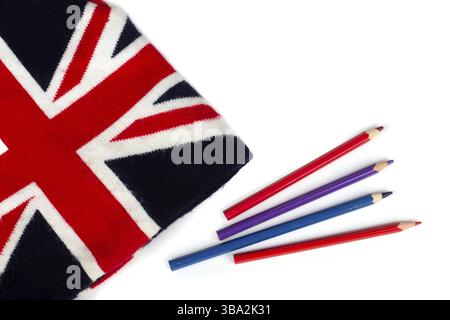 Winter knitted hat with a pattern of the UK flag and colored pencils on a white background Stock Photo