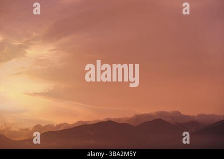 Orange and pink sky after sunset, silhouettes of mountains below - can be used as background with subjects placed in front, Liptovsky Hradok, Slovakia Stock Photo