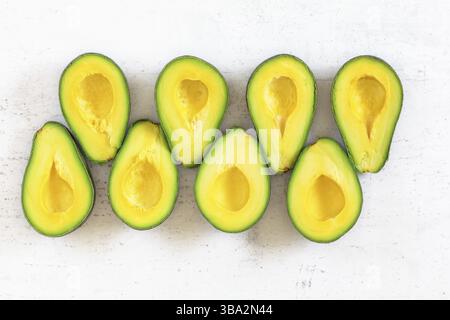 Tabletop view - avocado sliced to halves, arranged in two rows on white working board, Liptovsky Hradok, Slovakia, Europe Stock Photo