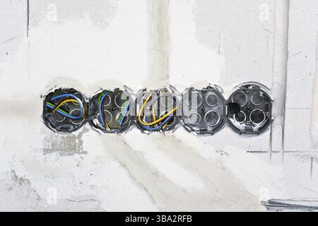 Boxes with cables for electric sockets installed in new house building empty wall Stock Photo