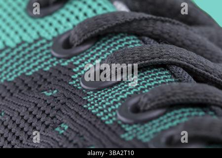 A fragment of a green sneaker with black laces close up. Sneaker texture Stock Photo