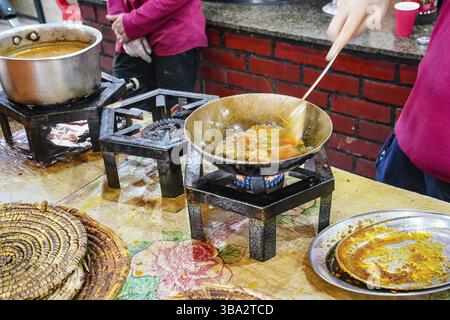 Lebensmittel, die auf einfachen Gasoefen im typischen pakistanischen Restaurant zubereitet werden, Kraeuter und Gewuerze in Stahlpfanne mit heissem Ge Stock Photo