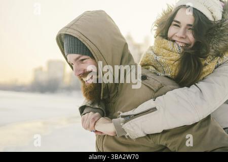 Thema Neujahr Weihnachten Stimmung Winter Schnee Feiertage Valentinstag. Junge kaukasische Paar Liebhaber Freude, Lachen Wasser im Stadtpark. Mann hae Stock Photo