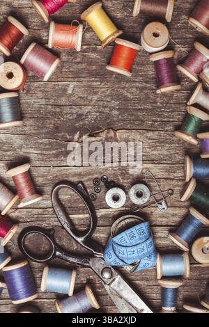 Retro scissors, textile and sewing threads on the wooden table with copy space Stock Photo