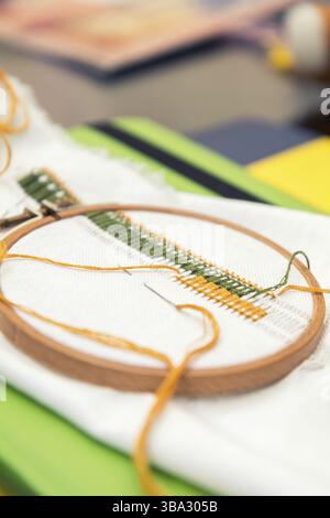 Work in progress. Ukrainian embroidery on the linen fabric and thread embroidery on a table, selective focus. Shallow depth of field Stock Photo