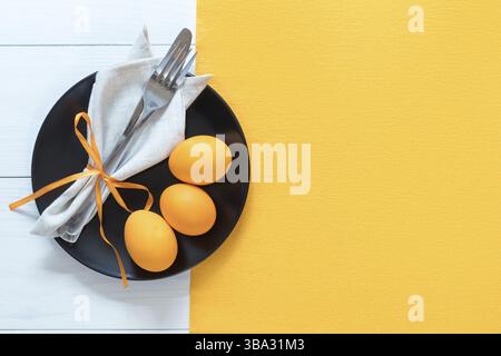 Easter table setting with cutlery. Rustic orange table cloth on white wood background. Holidays background with copy space Stock Photo