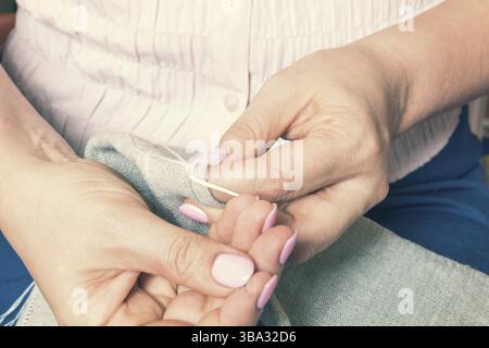Woman hands doing openwork embroidery on homespun linen. Close up. Coloring and processing photos Stock Photo