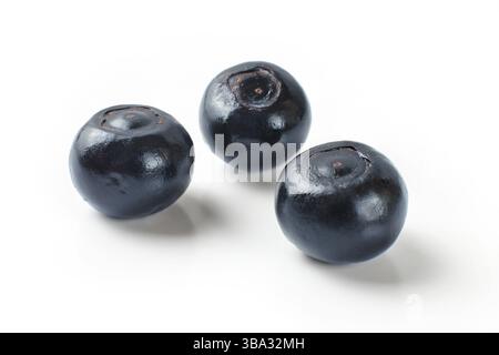 Three shiny dark blue blueberries isolated on white background Stock Photo