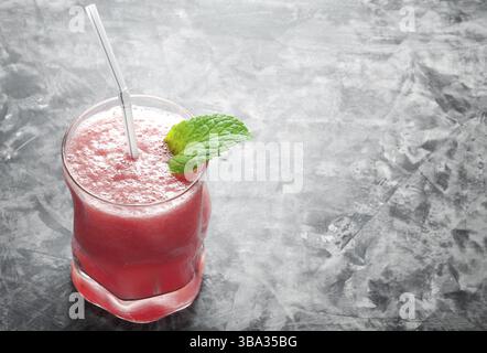 Tropical cocktail. Smoothie with mint, slices of watermelon and ice cubes on a gray concrete surface. View from above. Copy space Stock Photo