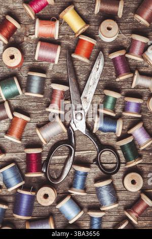 Retro wooden sewing spools with colourful threads and vintage scissors Stock Photo
