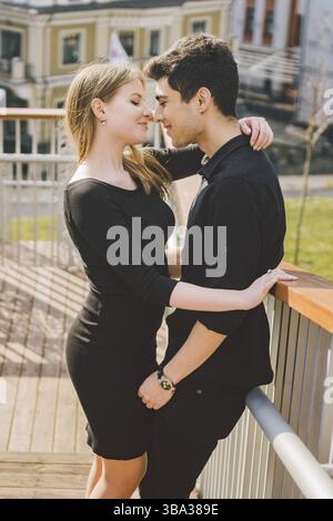 Beautiful young multiracial couple, a couple of students walk on the stairs in Kiev in the city center. Handsome Turkish brunette guy hugging, holding Stock Photo