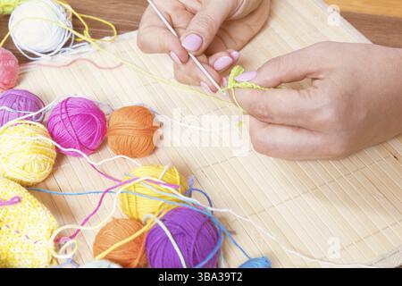 Colorful clews yarn and crochet hook on wooden background. Female hand crocheting. Toned and processing photos Stock Photo