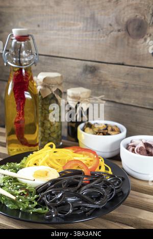 Hiyashi wakame with sesame and nut sauce, black and corn noodles, boiled egg. Octopus and mussels in ceramic bowls, bottle of olive oil with chili pep Stock Photo