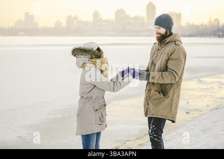 Young couple cheerfully flounders in snow. Between comic fight. Happy young couple hugs in winter snowy woods. Romantic lifestyle men and women in lov Stock Photo