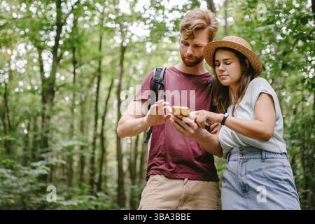 Hikers using mobile gps for directions. Happy couple checking smartphone in the woods during backpacking trip. Young joyful couple using gps map, navi Stock Photo