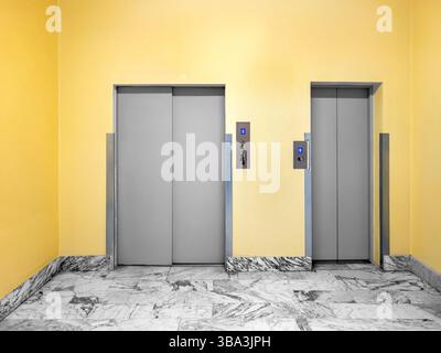 Public and service elevator doors in lobby with yellow walls and white marble floor Stock Photo