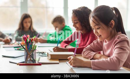 Japanese Schoolgirl Taking Notes Writing Essay Learning In Classroom, Panorama Stock Photo
