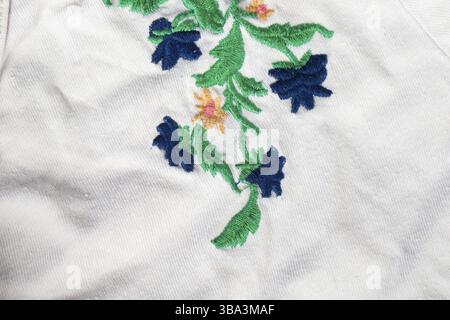 A piece of white cotton fabric with embroidered bright flowers Stock Photo