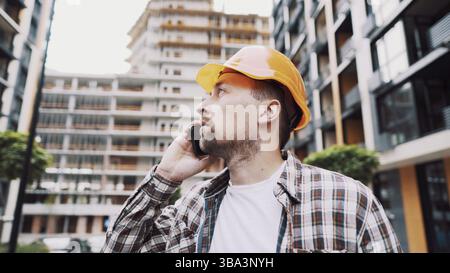 Engineer talking on phone. Architect using phone on construction site. Foreman phone call control process. Construction worker communications in const Stock Photo