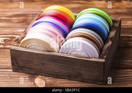 Various colors ribbon bobbins in vintage wooden box Stock Photo