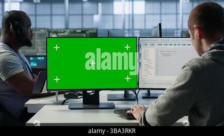 Engineer in server hub using green screen PC to repair equipment storing datasets. Professional using mockup computer to do debugging on rigs doing computational operations, camera A Stock Photo