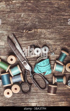Retro scissors, textile and sewing threads on the wooden table Stock Photo