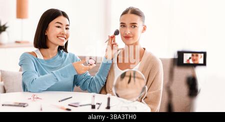 Asian Woman Doing Makeup For Her Beautiful Model Stock Photo