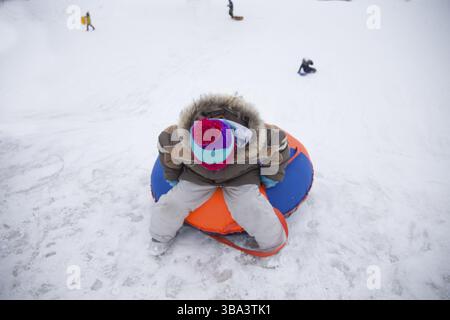 Sledding.Happy child on vacation. Winter fun and games.Little boy enjoying a sleigh ride.Children play outdoors in snow. Kids sled in the Alps mountai Stock Photo
