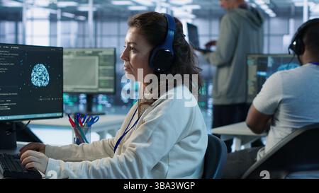 Developer listening music while programming in AI data center used for machine learning training. IT specialist wearing headphones running code to upgrade artificial intelligence tech, camera A Stock Photo