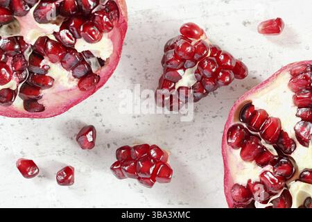 Tabletop closeup view - pomegranate half, clusters of gem like fruits scattered on white board, Liptovsky Hradok, Slovakia, Europe Stock Photo