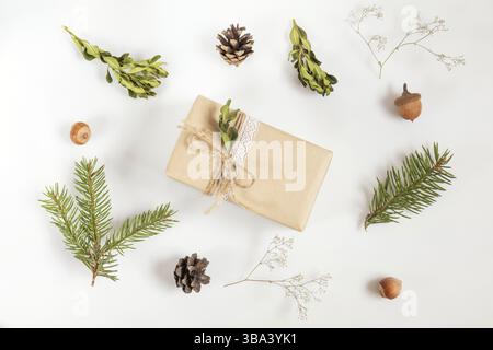 Christmas and New Year composition. Christmas gift, fir tree and buxus boxwood branches, acorn, hazelnuts, cones and gypsophila flowers. Flat lay on w Stock Photo