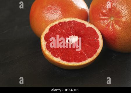 Pink grapefruit cut in half, whole citrus fruits in background on black board, Liptovsky Hradok, Slovakia, Europe Stock Photo