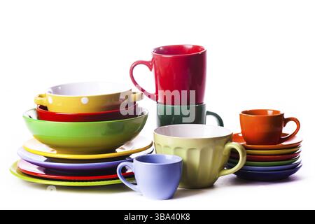 Big stack of different colors mugs and plate on white background, one above the another Stock Photo