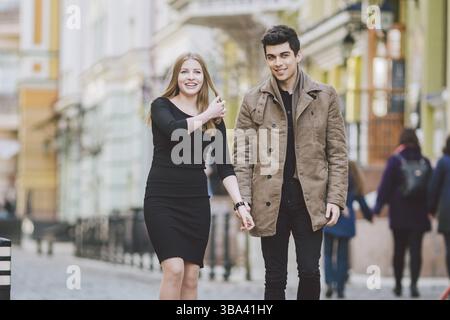 Urban modern young love couple walking romantic talking talking, holding hands on a date. Young multicultural Turkish brunette and Caucasian couple on Stock Photo