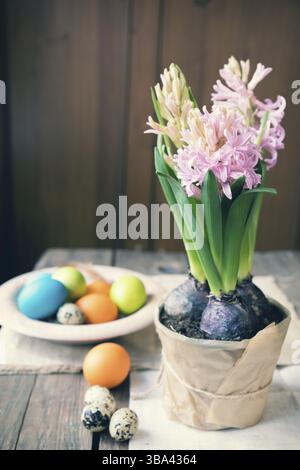Pink hyacinth, easter colorful and quail eggs in wooden pot on dark wooden table. Toned photo Stock Photo