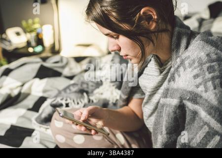Subject disease and technology. Young Caucasian woman uses mobile phone search information, buy medications through Internet, online connections with Stock Photo