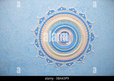 Round beautiful stucco pattern on the ceiling. Relief plaster, relief pattern blue background. Part of an old ceiling decorated with a clay pattern Stock Photo